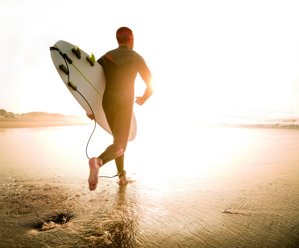 A surfer with his surfboard running to the waves