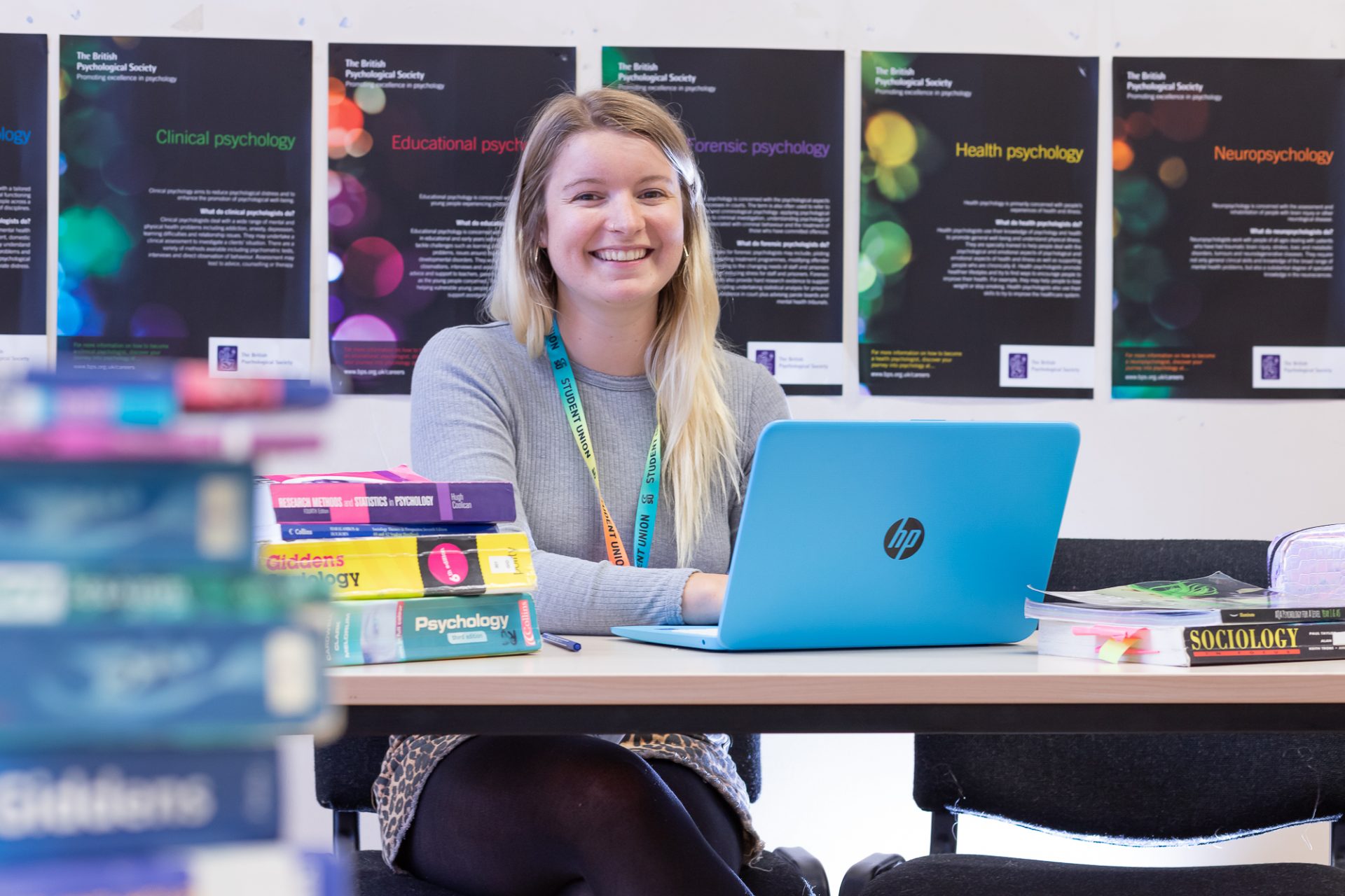 Woman sitting at desk with laptop and biology text books