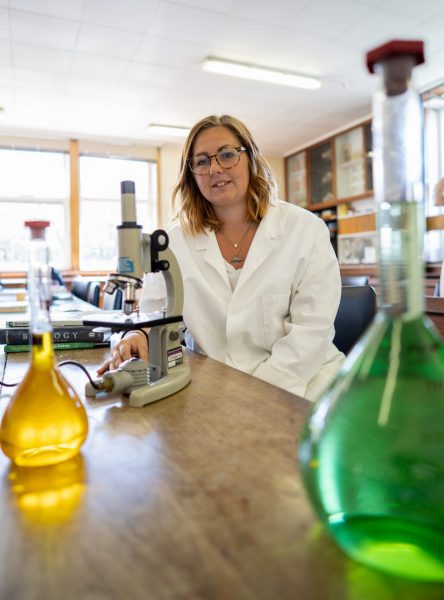 Wide shot of girl in science lab at microscope