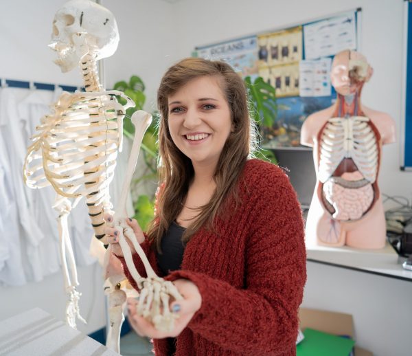 Girl holding skeleton in healthcare training environment