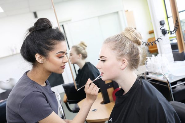 Cornwall College beauty student applying lipstick to a model