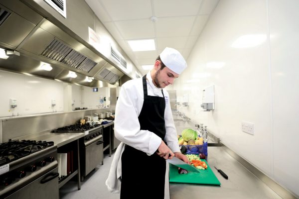 Cornwall College Catering student in the kitchen prepping vegetables