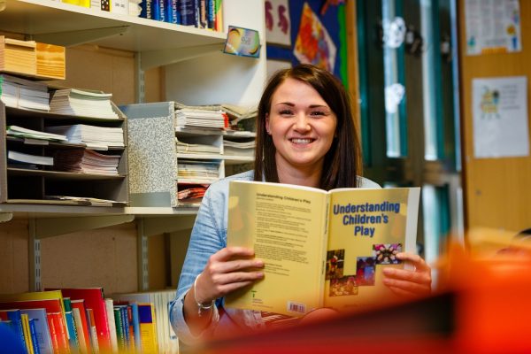 Early years student reading a book about child development and play at Cornwall College