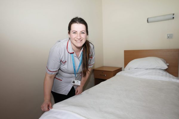 Healthcare assistant for Cornwall Care making a bed in a care home