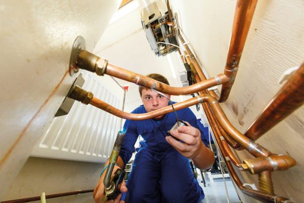 A plumbing student welds a copper pipe