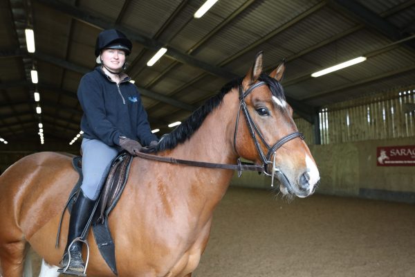 Equine student sits on a horse in indoor arena