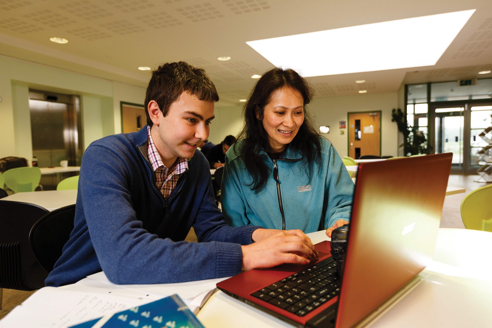 Student and tutor smiling looking at a laptop