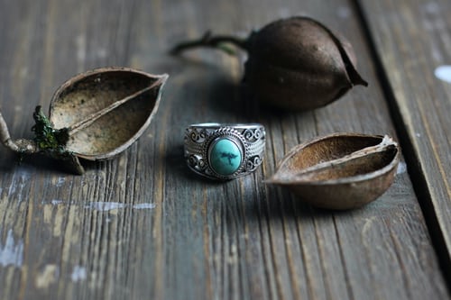 Silver ring set with a blue stone on a wooden bench