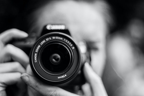 Black and white close up image of a man holding a camera