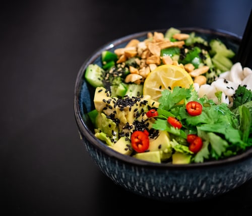 Vegan mixed vegetable dish in a blue bowl on a black background.