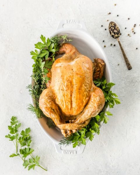 Roast chicken in a serving dish with herbs