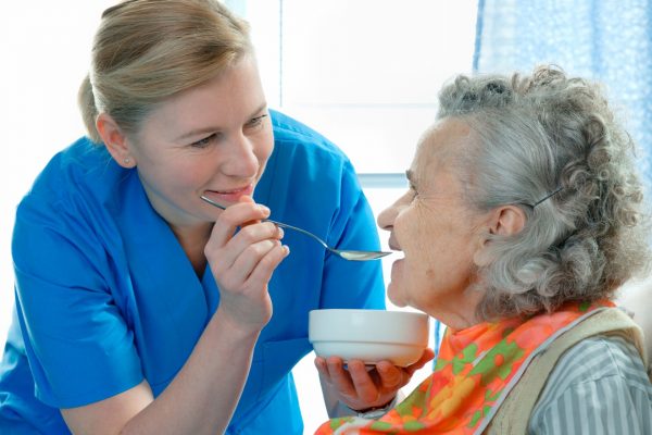 Senior woman being fed by a care worker