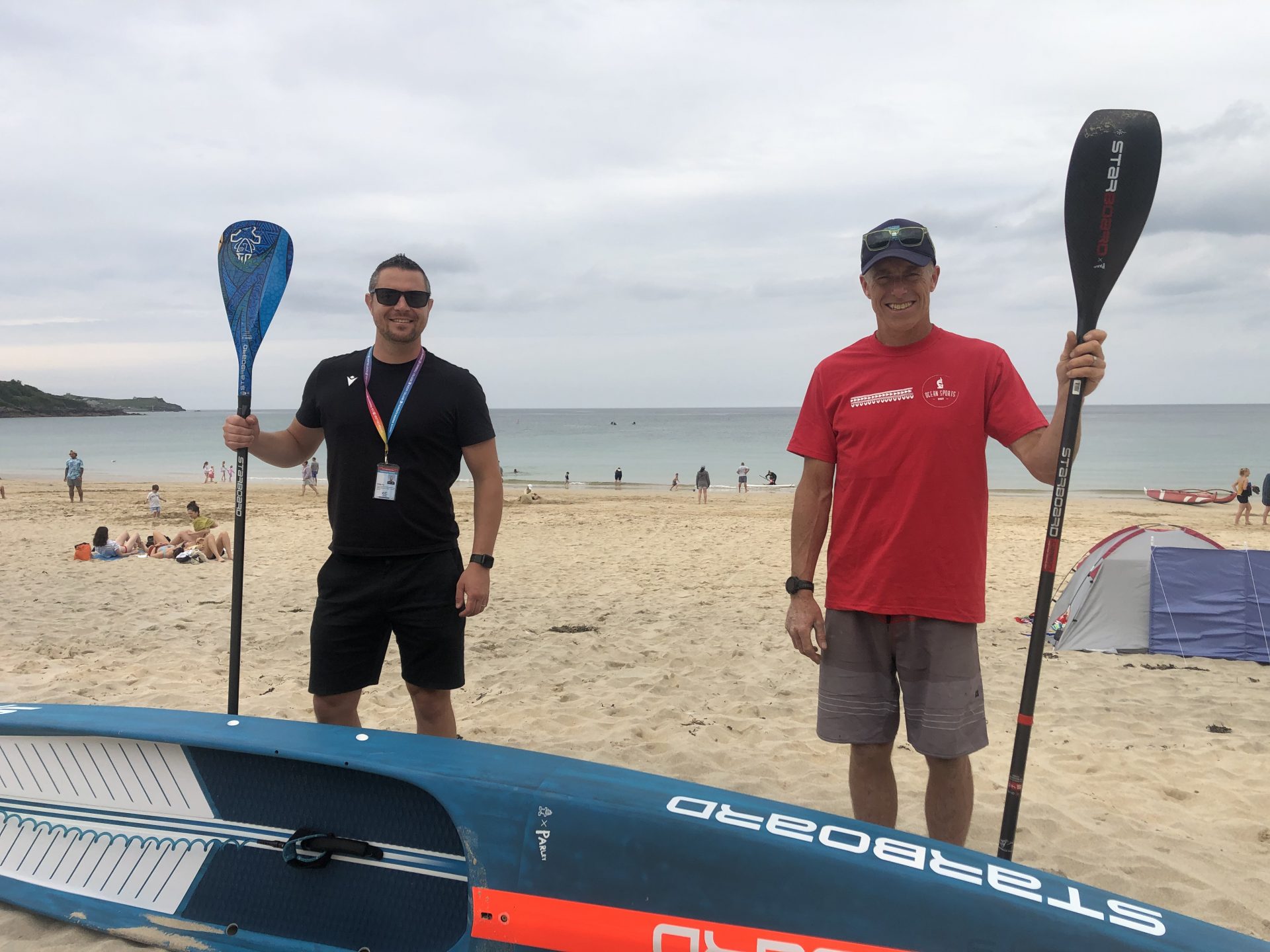 Two people holding paddles in front of a paddle board