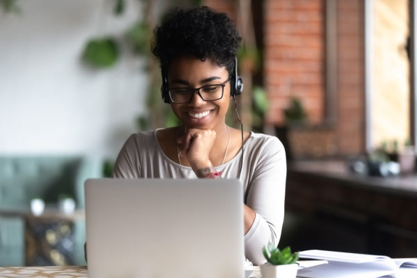 A smiling student in front of a laptop on an online course