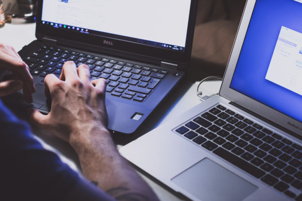 Cybersecurity professional working on two laptops