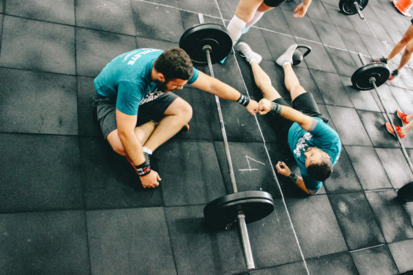 A gym instructor high-fives a student before weightlifting