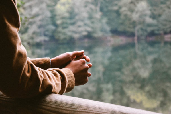 A closeup photo of someone's hands with a forest in the background