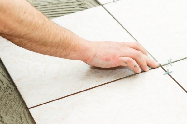 A person's hand fixing floor tiling