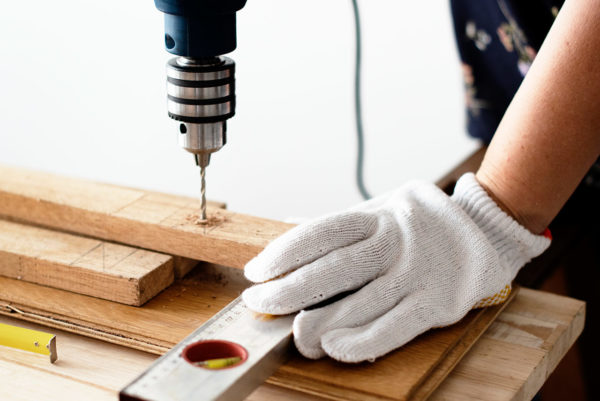 Someone drilling holes in timber using an electric drill and spirit level