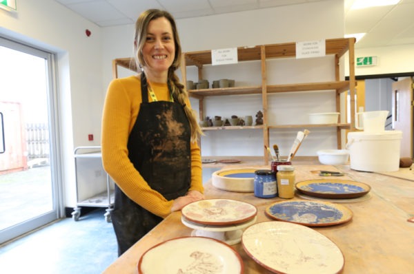 Smiling student showing her ceramic work.