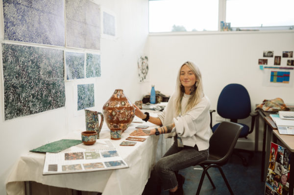 Student sitting by a desk, which displays her ceramic work.