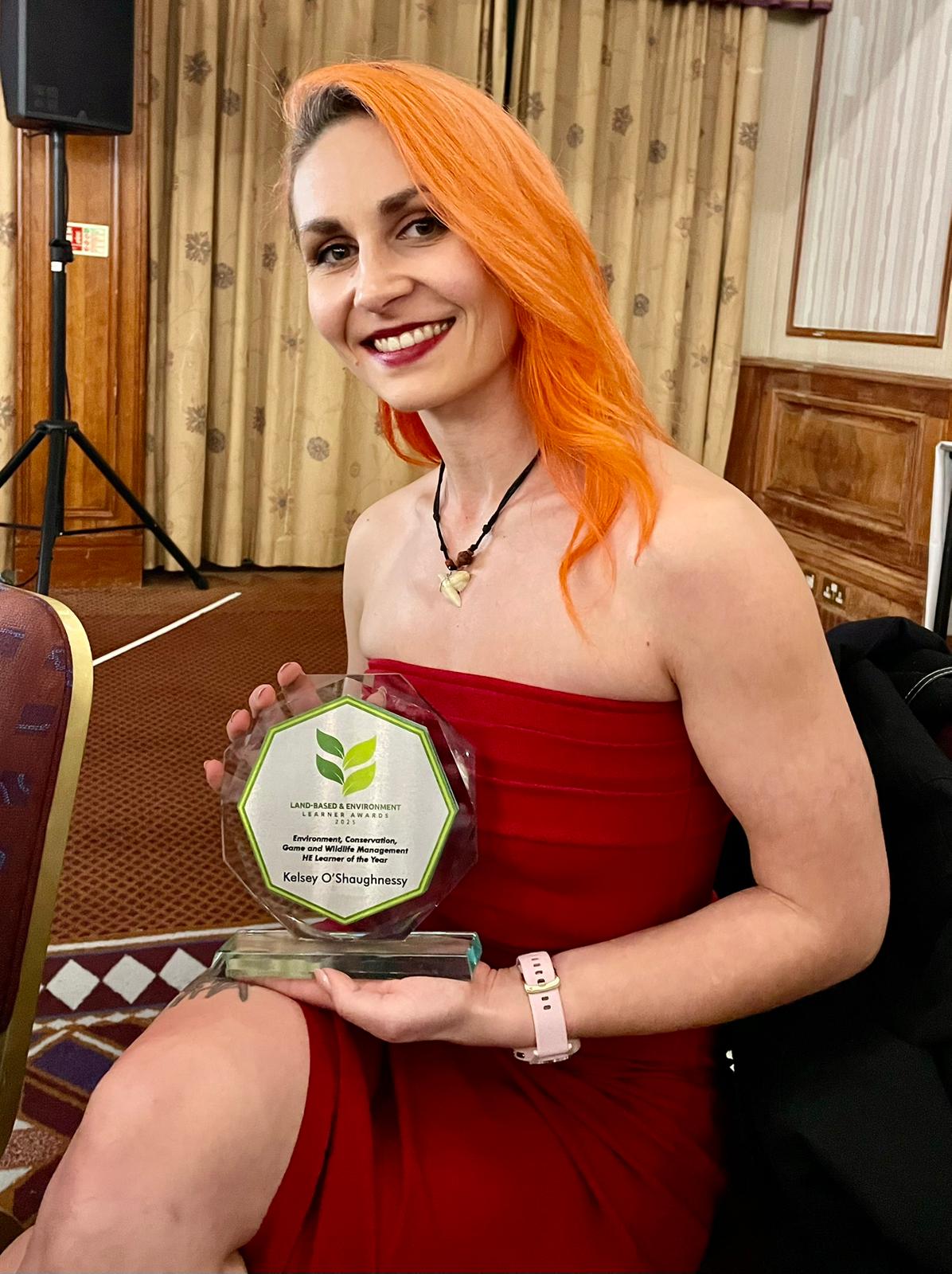 Kelsey sat on a chair with her award